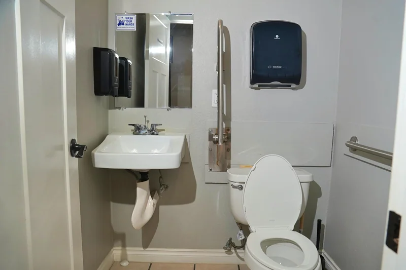 An accessible bathroom with grab bars beside the toilet and basin