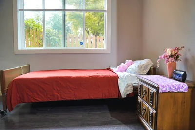 A resident bedroom at Bear Care AFH II with a window over the garden