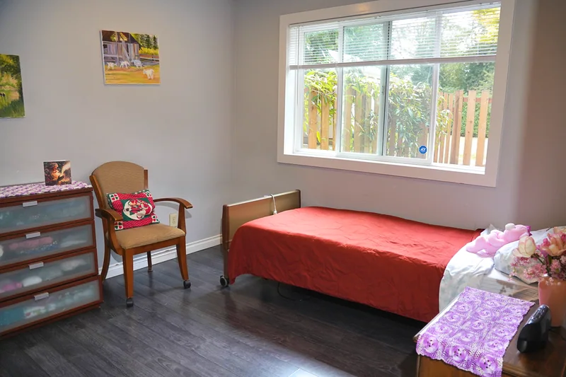A resident bedroom with a chair beside the bed