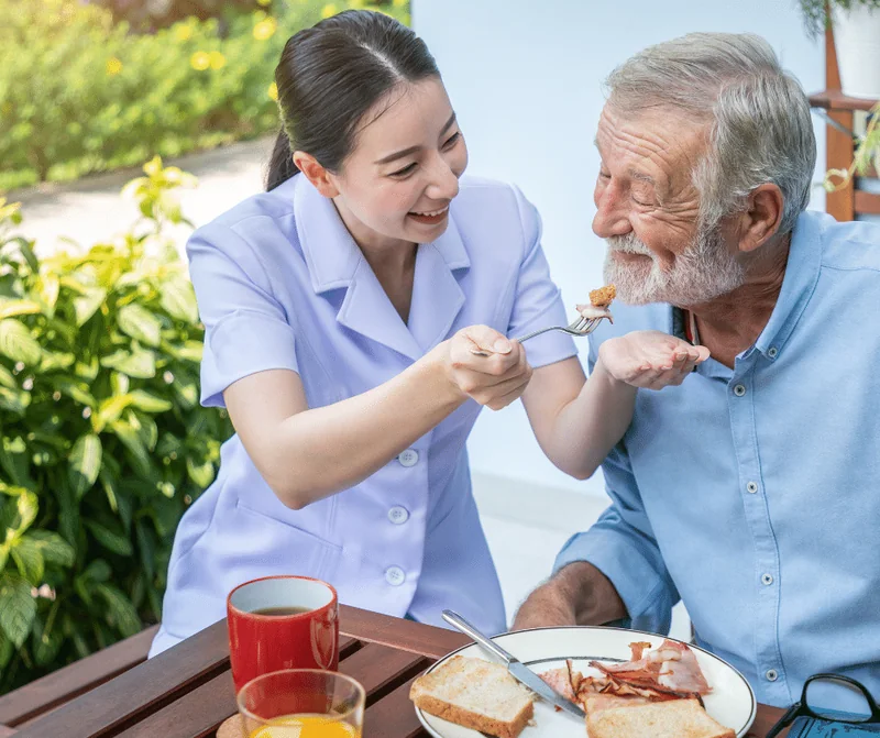 Stock image: a caregiver helping an older adult with a meal
