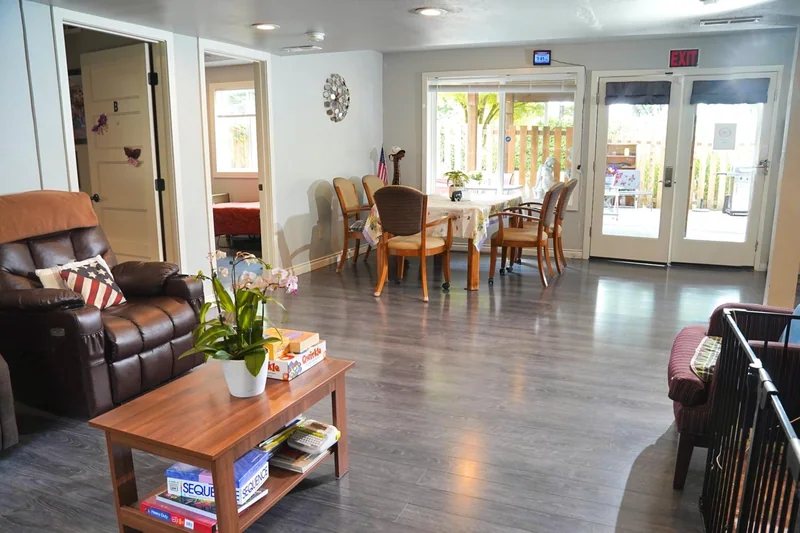 A recliner in the living room at Bear Care AFH II, with the dining table beyond