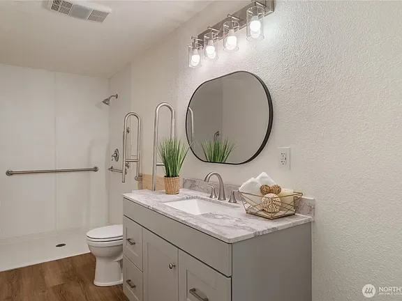 Accessible bathroom with grab bars, a step-free shower and a vanity