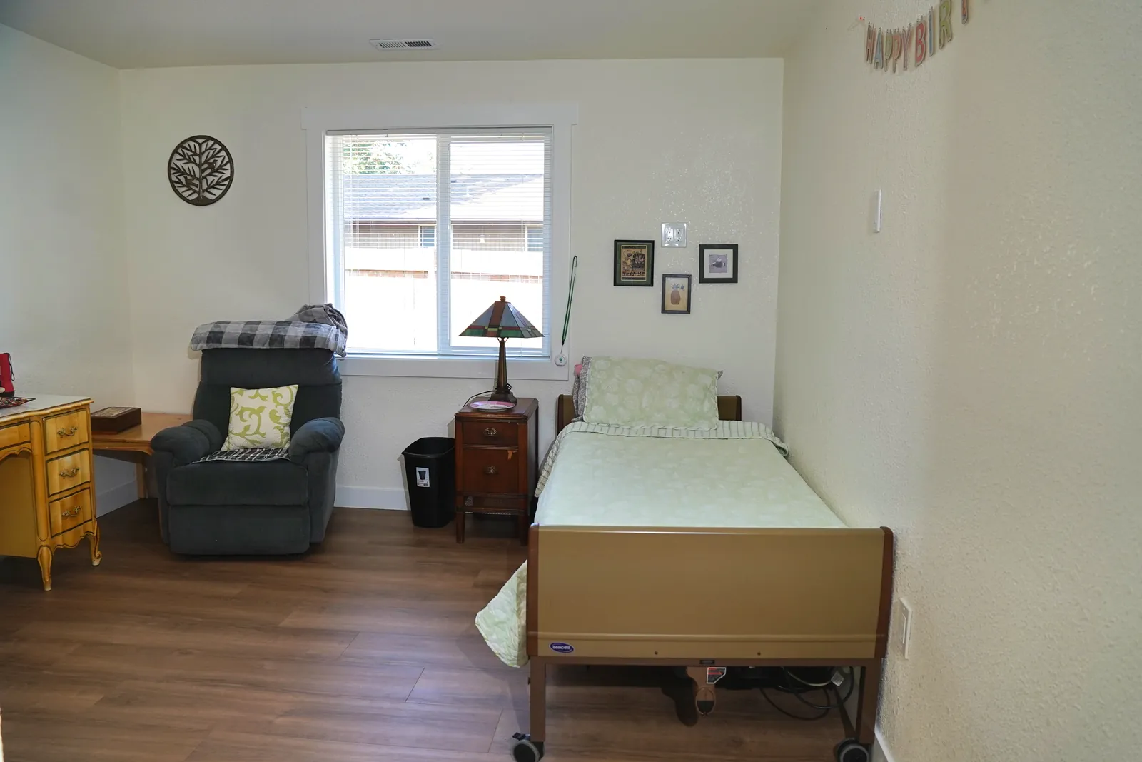 Bedroom with a bed, armchair and a lamp beside the window