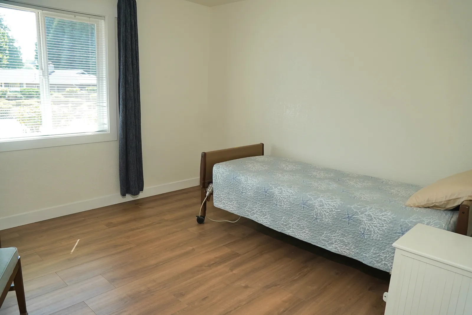 Bedroom corner with a bed beside a curtained window