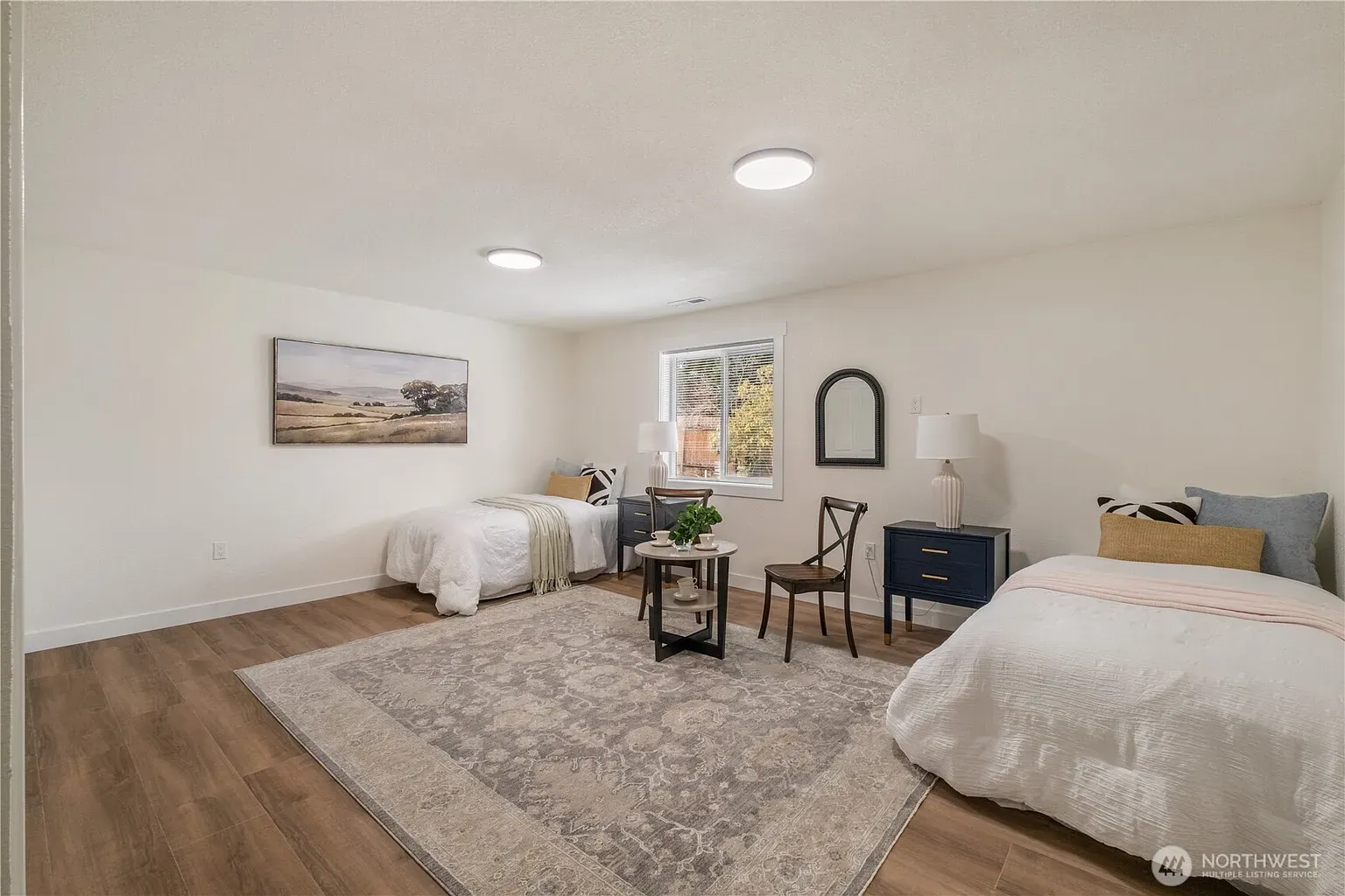 Bedroom with two made beds, a rug and a window