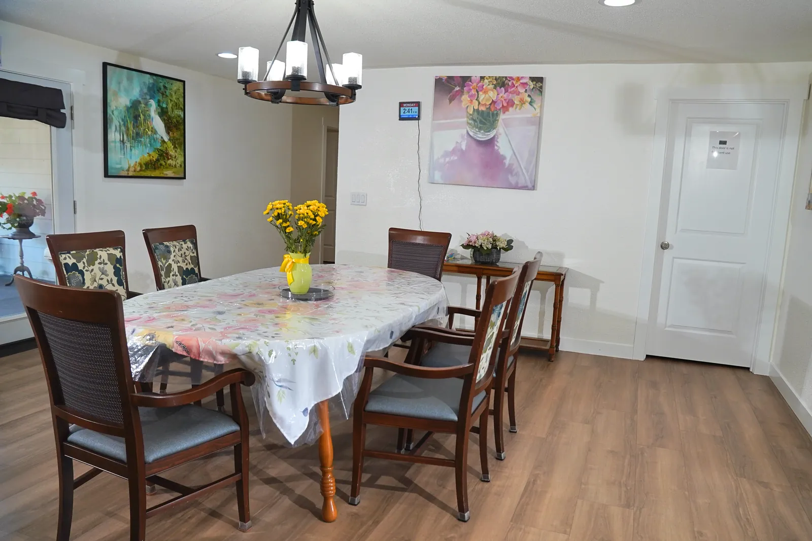 Dining table set with a cloth and flowers beneath a chandelier