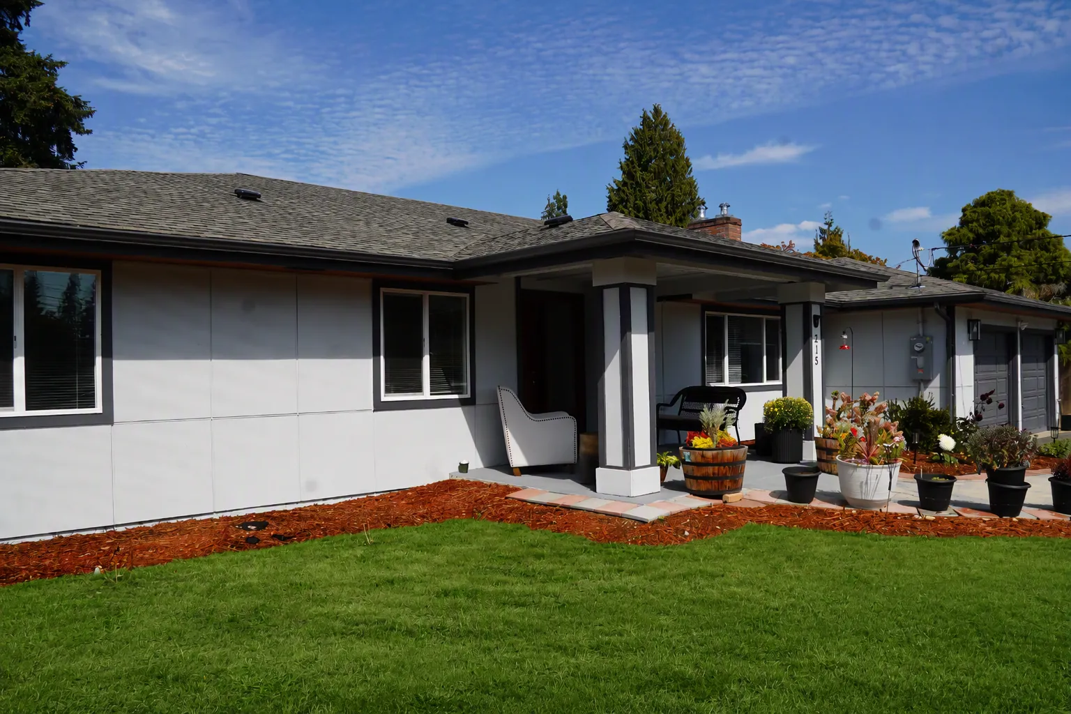 Covered entry porch with seating and potted plants beside the lawn